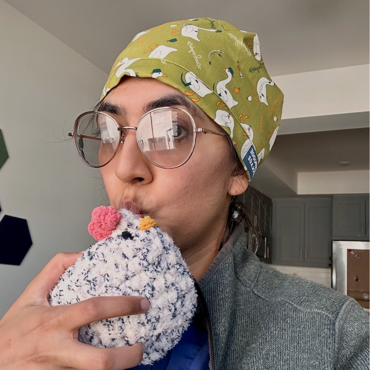 Person wearing a patterned scrub cap and holding a crocheted chicken