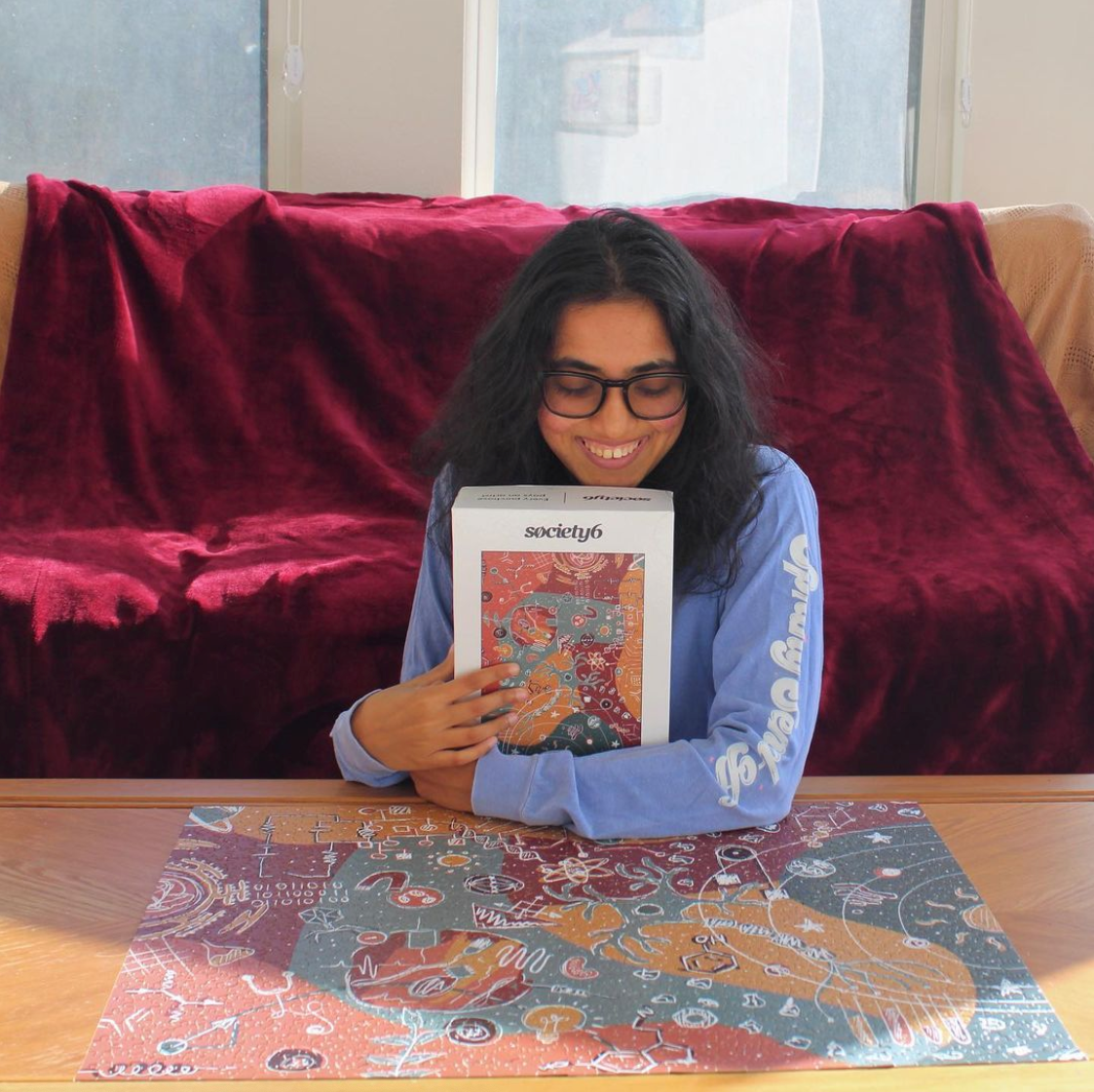 Sumana posing with a science themed puzzled from Society6